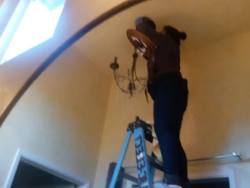 Electrician installing a chandelier in a Penrose residence